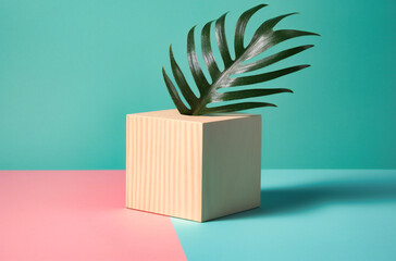 pink wooden cube with palm on a white and green surface