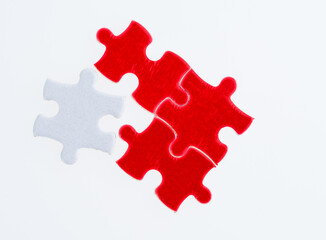 Three red and one white puzzle pieces on white background.
