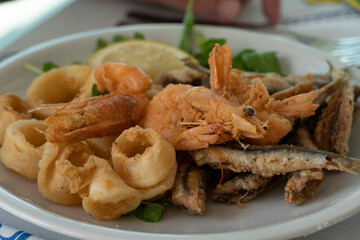 Fried calamari fishes and shrimps on plate in summer restaurant beach in Scalea Italy