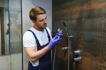 Professional handyman working in shower booth indoors