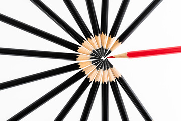 One red pencil standing out from the black pencils