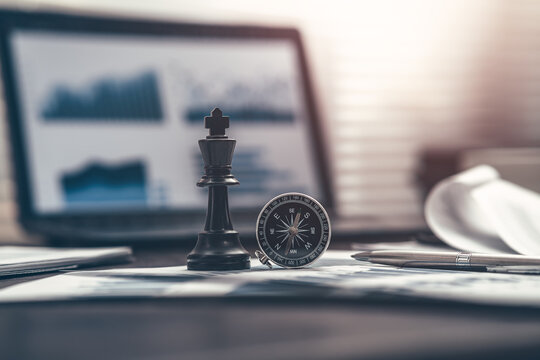 The King in chess pieces, compass and pen are placed on financial documents to signify being the best in business. Abstract  business concept.