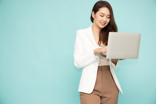 Asian Business Woman In Suit Holding A Laptop While Standing Isolated On Green Background