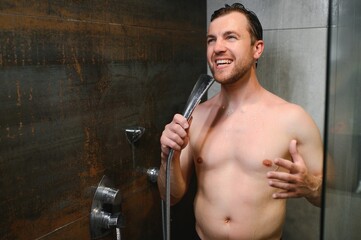 Fototapeta na wymiar Young single handsome caucasian man are taking shower in the bathroom, he is singing, happy and relaxed.