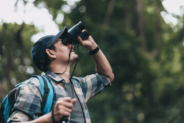 Fototapeta premium Hikers use binocular to see animals and view landscape with backpacks in the forest. hiking and adventure concept.