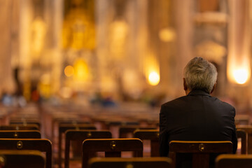 Fototapeta An elderly man sits on a chair in a church obraz