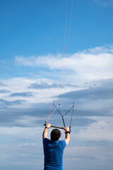 man holding sports kite flying, blue sky, summer
