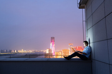 Businessman sitting on the rooftop and using laptop - Powered by Adobe