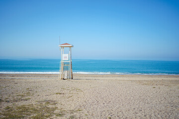 Scenic view of empty bay watch tower on a lonely seaside beach. Scenery landscape of a sea ocean shore with wooden abandoned lifeguard tower