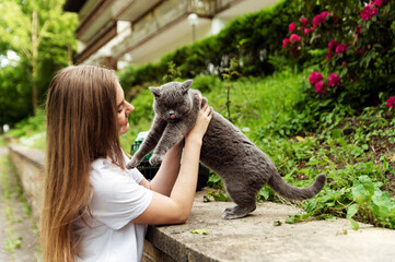 a beautiful girl gently hugs her beloved cat while being outside in nature. walking with a pet