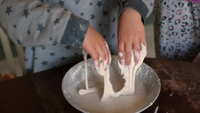 Newtonian fluid. Smart Curious School Children Playing With Homemade Water and Corn Starch Based Mixture Non Newtonian Oobleck Fluid STEM. Slime, fused learning. KIds doing a fun science experiment.