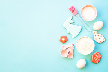 Easter baking background on blue. Flour, edds, sugar and gingerbread cookies. Top view with copy space.