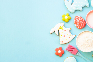 Easter baking, Flour, edds, sugar and gingerbread cookies. Top view on blue.