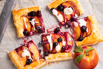 Portions of nectarine and blueberry puff pastry pie with vanilla glaze