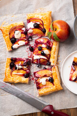 Top view of nectarine and blueberry puff pastry tart in portions