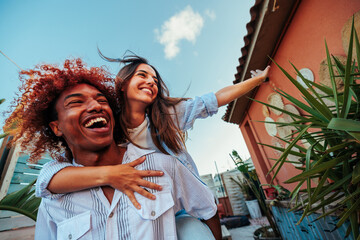 Multiracial friendship couple having fun together outside the house. - obrazy, fototapety, plakaty