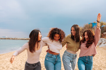 Four diverse best girl friends jumping together on beach.
