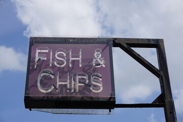 Obraz premium Vintage style fish & chips sign outside takeaway in English seaside town. Typically British food 