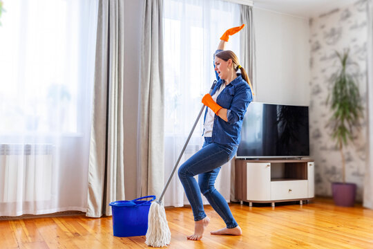 Happy Young Woman With Mop Singing, Dancing And Having Fun While Cleaning Floor