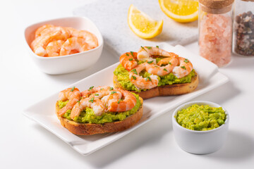 Appetizer toasted bruschetta with mashed avocado and shrimps on background. Healthy food concept with prawns.
