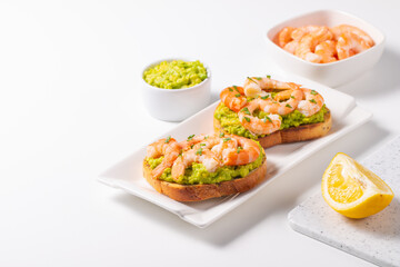 Appetizer toasted bruschetta with mashed avocado and shrimps on background. Healthy food concept with prawns.