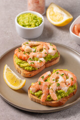 Appetizer toasted bruschetta with mashed avocado and shrimps on background. Healthy food concept with prawns.