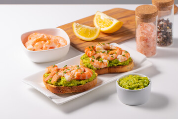 Appetizer toasted bruschetta with mashed avocado and shrimps on background. Healthy food concept with prawns.
