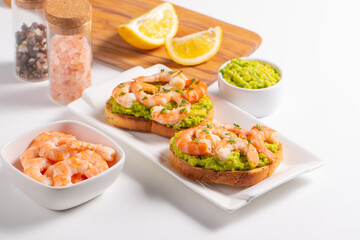 Appetizer toasted bruschetta with mashed avocado and shrimps on background. Healthy food concept with prawns.