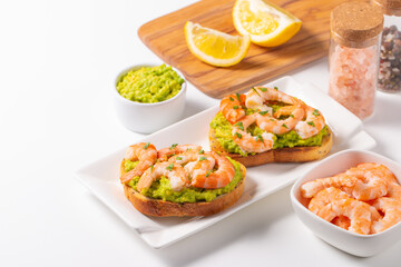 Appetizer toasted bruschetta with mashed avocado and shrimps on background. Healthy food concept with prawns.