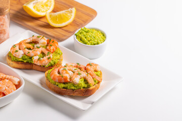 Appetizer toasted bruschetta with mashed avocado and shrimps on background. Healthy food concept with prawns.