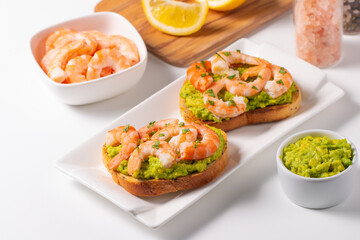 Appetizer toasted bruschetta with mashed avocado and shrimps on background. Healthy food concept with prawns.