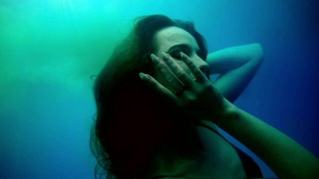 woman sinking in depth, underwater slow motion shot, beautiful face and long hair