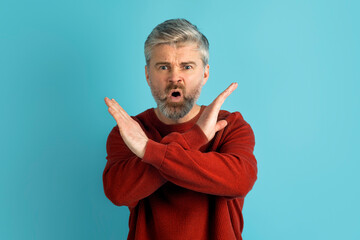Image of angry middle aged man making cross hands gesture
