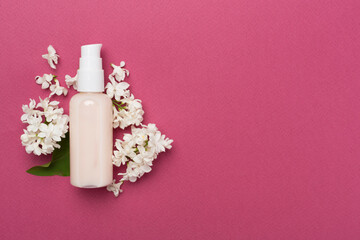 Composition with cosmetic bottle and flowers on color background, top view