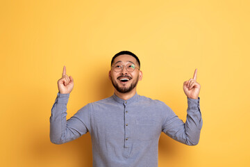 Place For Ad. Excited young asian man pointing up at copy space