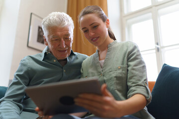 Senior man with his granddaughter using digital tablet. - obrazy, fototapety, plakaty