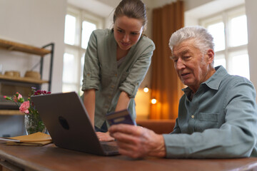 Senior man with his granddaughter online shopping at notebook.