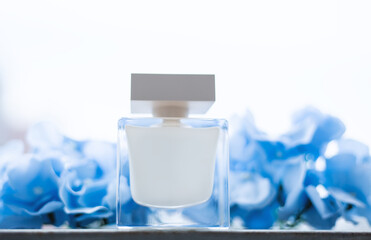 Perfume in a glass bottle on a blue flower petals background