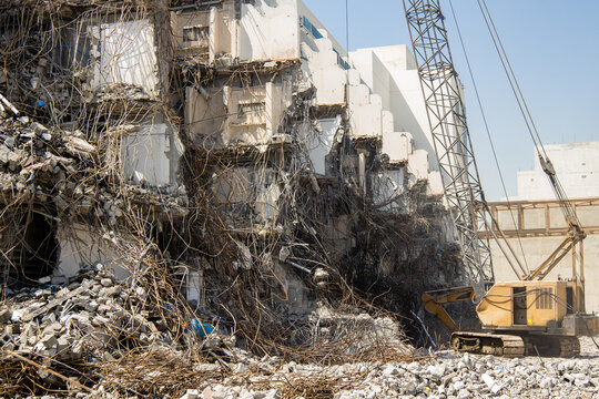 wrecking ball crane demolishing an old building. Dust and debris fill the air as the structure crumbles, leaving behind a scene of destruction and a pile of rubble