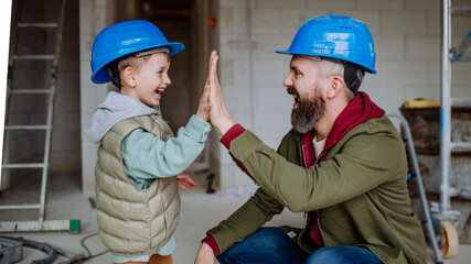 Father and his little son working on their unfinished house.