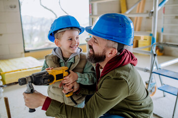 Father and his little son working on their unfinished house.