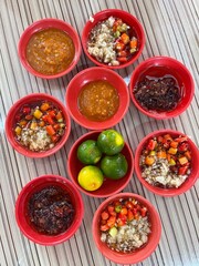 Asian condiments: fresh cut chillis, garlic, shrimp chili paste belacan, chili sauce, soy sauce, fresh green lime