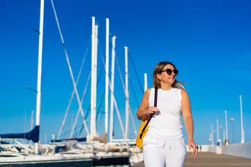 Fototapeta premium Beautiful woman on vacation walking in marina 
