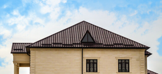 Roofs of houses made of metal slate against the sky. Modern metal roof. Metal tile and metal tile.