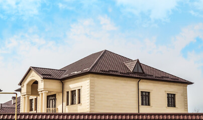 Fototapeta na wymiar Roofs of houses made of metal slate against the sky. Modern metal roof. Metal tile and metal tile.