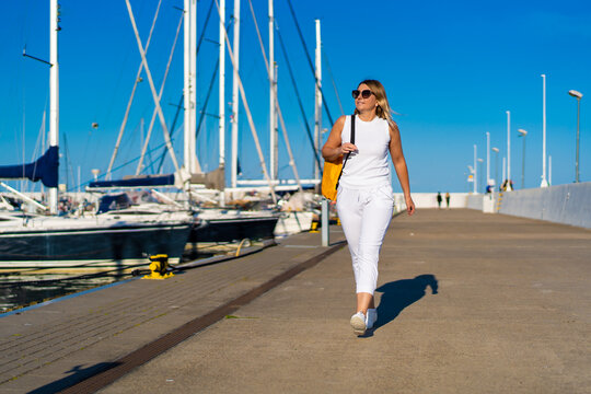 Beautiful woman on vacation walking in marina
 - Powered by Adobe