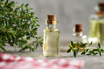 Thyme essential oil with fresh thyme plant on a table