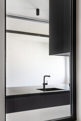 A skylight in a kitchen furnished with smooth black cabinets without handles