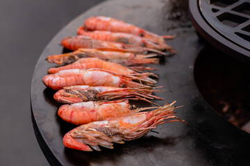 Process of cooking fresh red langoustine shrimps, prawns on grill at summer local food market - close up, selective focus. Outdoor cooking, barbecue, gastronomy, seafood and street food concept