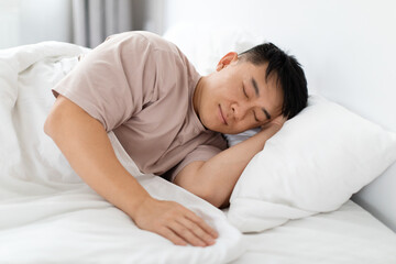 Fototapeta na wymiar Middle aged asian man sleeping alone in bed